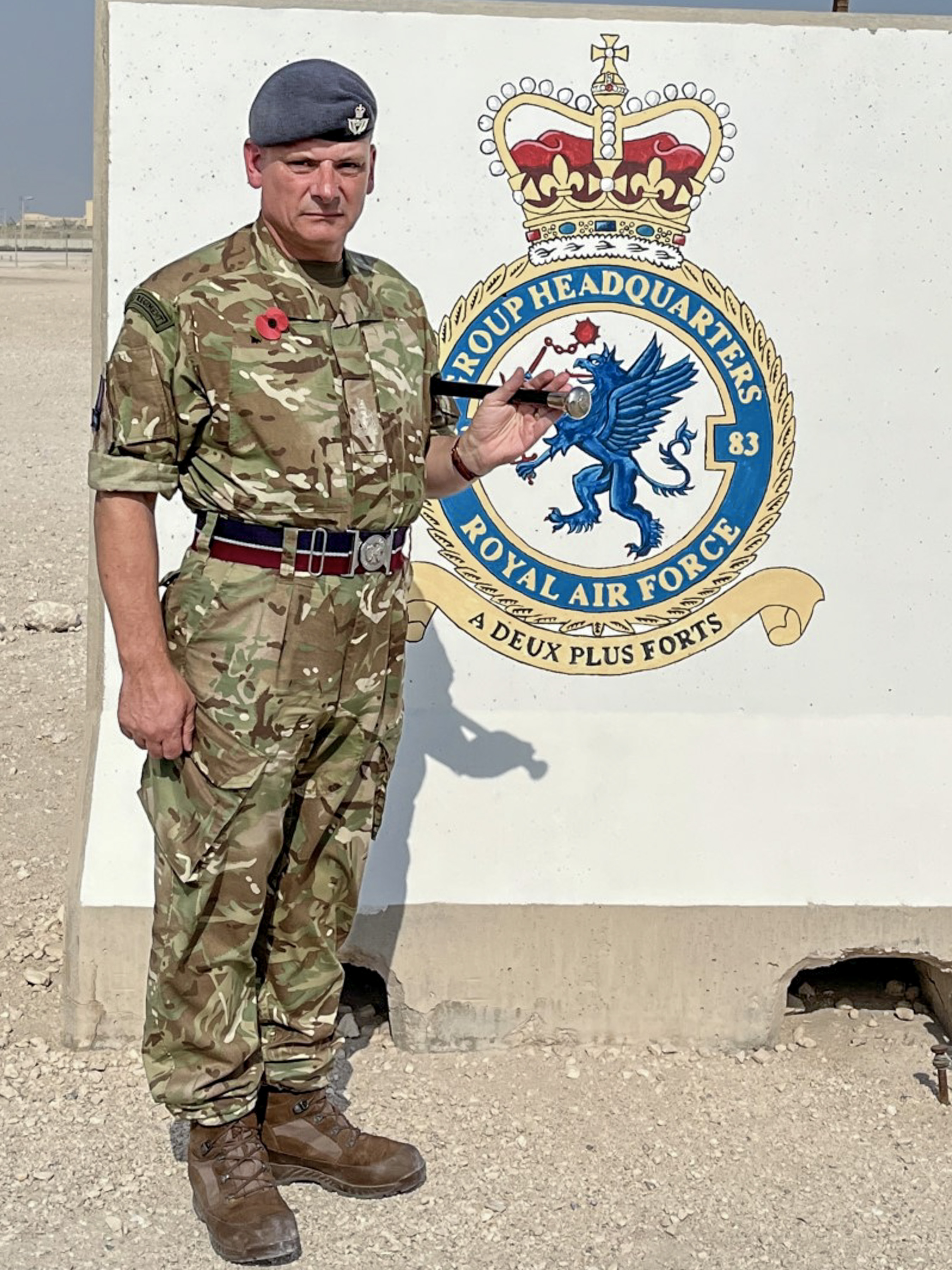 Image shows RAF personnel standing next to Squadron crest on a statue in Iraq. 